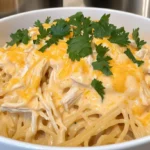 Close-up of creamy crockpot chicken spaghetti topped with melted cheese and parsley