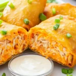 Close-up of buffalo chicken egg rolls with creamy spicy filling, served with ranch dip and veggie sticks.
